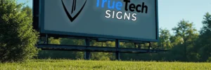 Outdoor billboard displaying the logo and text “TrueTech SIGNS” in a grassy area with trees in the background.